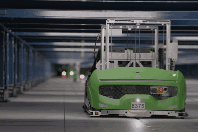 Robot verde autónomo que se desplaza por un pasillo de un almacén.