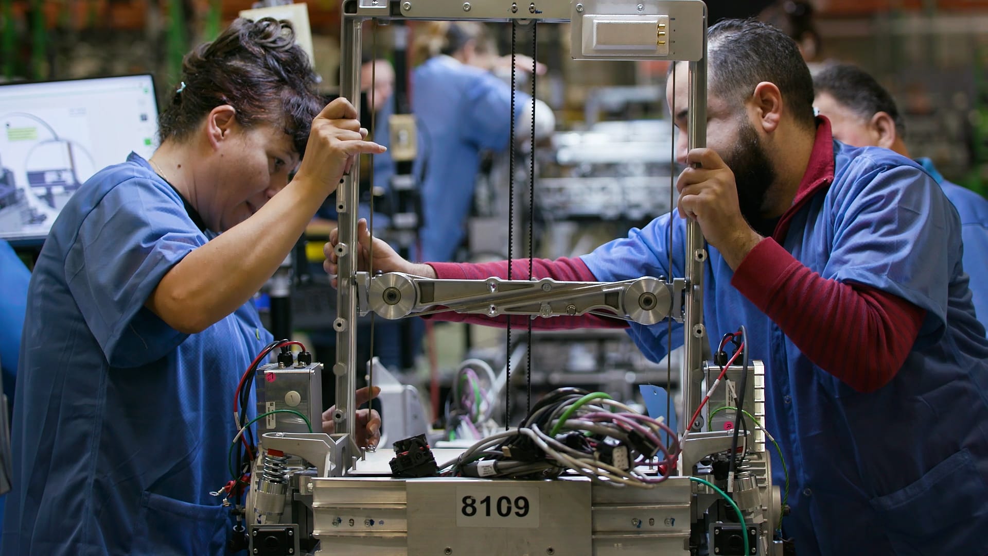 Trabajadores de fábrica que montan maquinaria con concentración y precisión en una ajetreada cadena de producción.