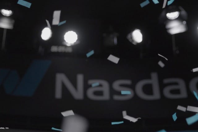 Biển hiệu sàn giao dịch chứng khoán Nasdaq với pháo hoa giấy và đèn chiếu sáng làm nền